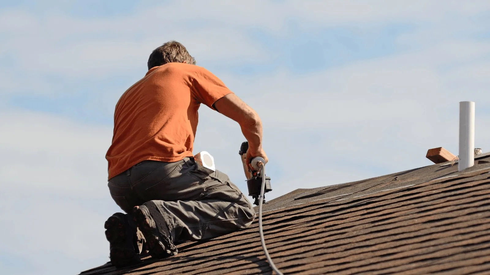 Roofing contractor installing shingles with a nail gun