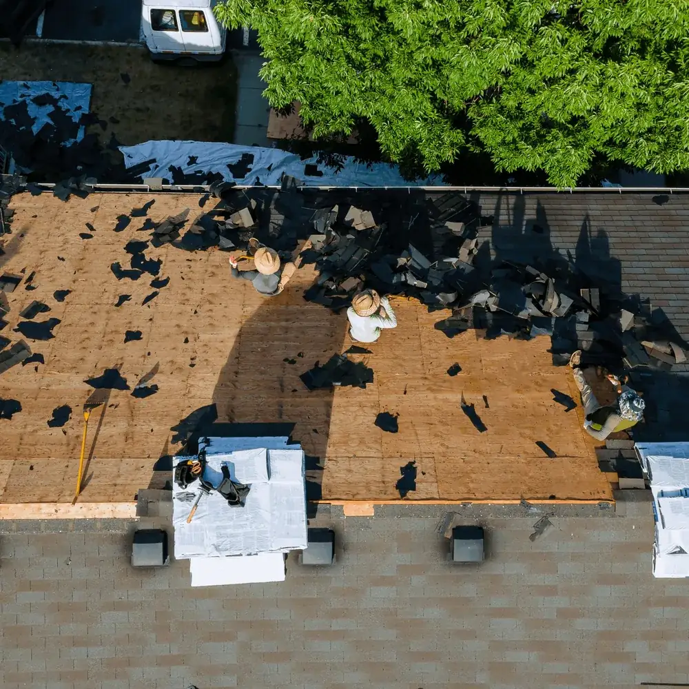 Roofer repairing asphalt shingles with hand tools
