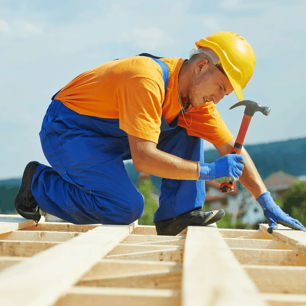 Roofer kneeling on a roof with tool belt during a job Roofer kneeling on a roof with tool belt during a job